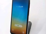 the back of a black phone with a blue screen on a white surface