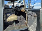 un camion vert dont la porte est ouverte, garé sur un parking