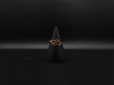 une bague en or sur une surface noire, avec un fond noir