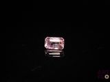 a close up of a pink diamond on a black surface