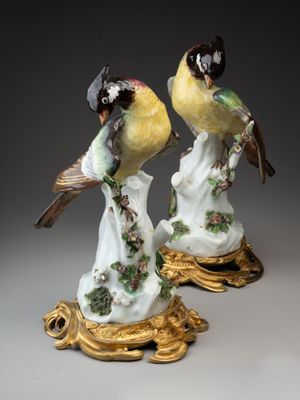 deux figurines d'oiseaux posées sur un socle en or