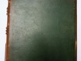 un vieux livre posé sur une table blanche à côté d'un mur blanc