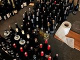 many bottles of wine sitting on the floor next to a roll of toilet paper
