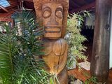 a wooden statue in the middle of a room with a potted plant in it