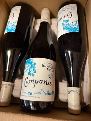 trois bouteilles de vin dans un carton sur une table