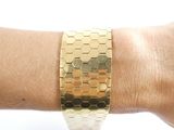 someone is wearing a gold bracelet with hexagons on it