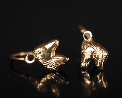 un gros plan sur une paire de boucles d'oreilles en or posées sur une surface noire
