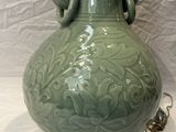 a large green vase with a handle on a stand