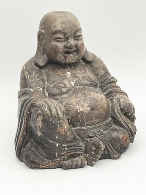 une vieille statue représentant un Bouddha souriant, assis sur une surface blanche