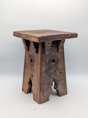 un vieux tabouret en bois troué, sur fond blanc
