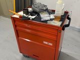 un petit chariot rouge sur lequel se trouvent de nombreux objets