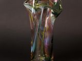un vase en verre transparent orné de volutes multicolores sur fond noir