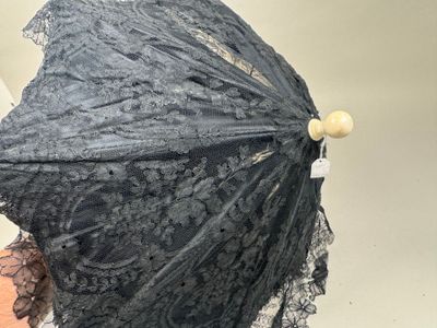 une femme tenant un parapluie en dentelle noire à la main