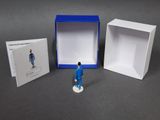 a small figurine of a man standing in front of a box