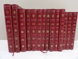 six livres rouges alignés sur une table blanche
