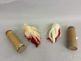 deux rouleaux de papier toilette et une plume rouge et blanche posée sur une surface blanche