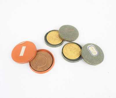 quatre petites boîtes contenant des pièces de monnaie, posées sur une surface blanche