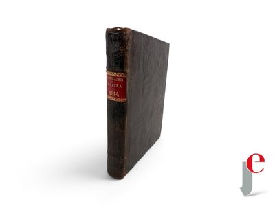 an old book sitting on top of a white surface with a red cover