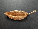 broche en feuille d'or sur un support noir avec un fond noir