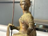 a statue of a woman sitting on a chair holding a pole