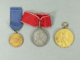 three medals and a ribbon on a gray surface