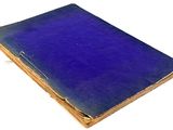 an old book with a blue cover sitting on top of a white surface