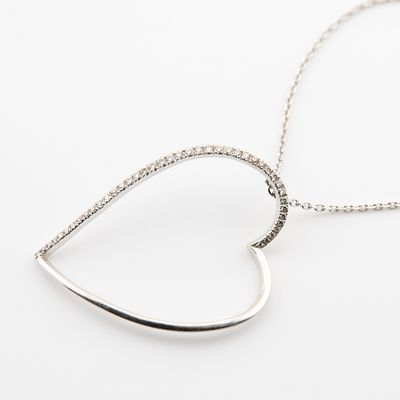un pendentif en forme de cœur en argent avec une chaîne, sur fond blanc