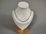 silver chain necklace on a wooden stand on a gray background