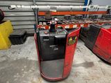 a red forklift in a warehouse with other pallets