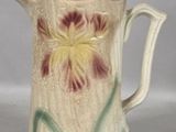 a small pitcher with a flower painted on it