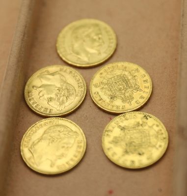 quatre types différents de pièces d'or dans une boîte posée sur une table
