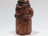 wooden statue of a man with a hat and a cane on a white pedestal