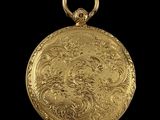 an antique gold pocket watch on a black background with a black background