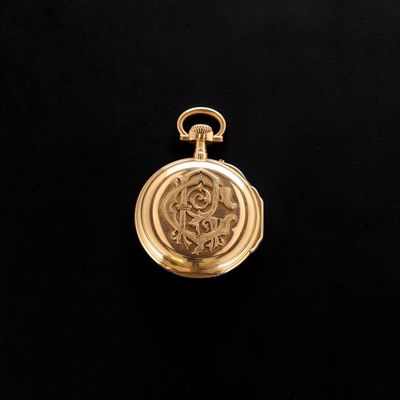 a gold pocket watch on a black background with a black background