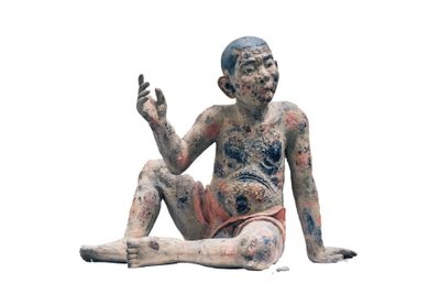 une statue représentant un homme assis par terre, les mains levées