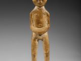 une petite figurine en bois représentant un homme, les mains dans les poches
