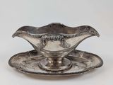 une assiette en argent posée sur une soucoupe, avec une autre soucoupe à côté