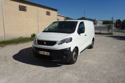 La camionnette blanche est garée sur le parking près d'un immeuble.