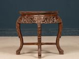 an old wooden table with a carved top on a floor