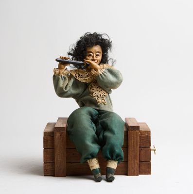 une figurine représentant une femme assise sur une caisse en bois