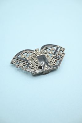 a close up of a silver brooch with a heart on it