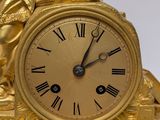a gold clock with a statue on top of it