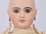 an old doll with a bald head wearing a dress and a pair of earrings