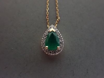 un gros plan d'un collier composé d'une pierre verte montée sur une chaîne