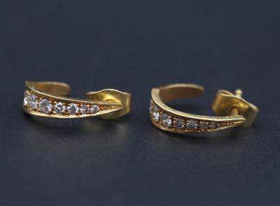 une paire de boucles d'oreilles en or et diamants sur une surface noire