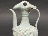 a white vase with a bird on it on a table