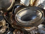 a pile of silver plates and silver spoons on a table