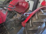 a red tractor parked in a garage next to a green truck