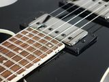 a close up of a black electric guitar on a white surface