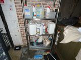 a metal shelving in the corner of a room with a lot of stuff on it